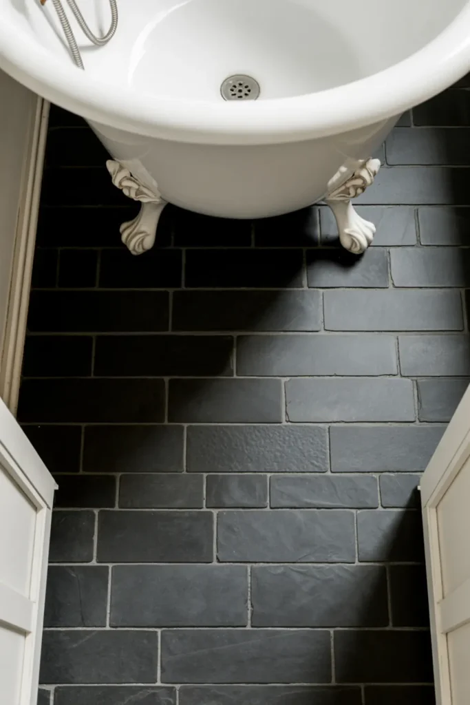 Textured natural black slate bathroom floor tiles laid in a classic herringbone pattern.