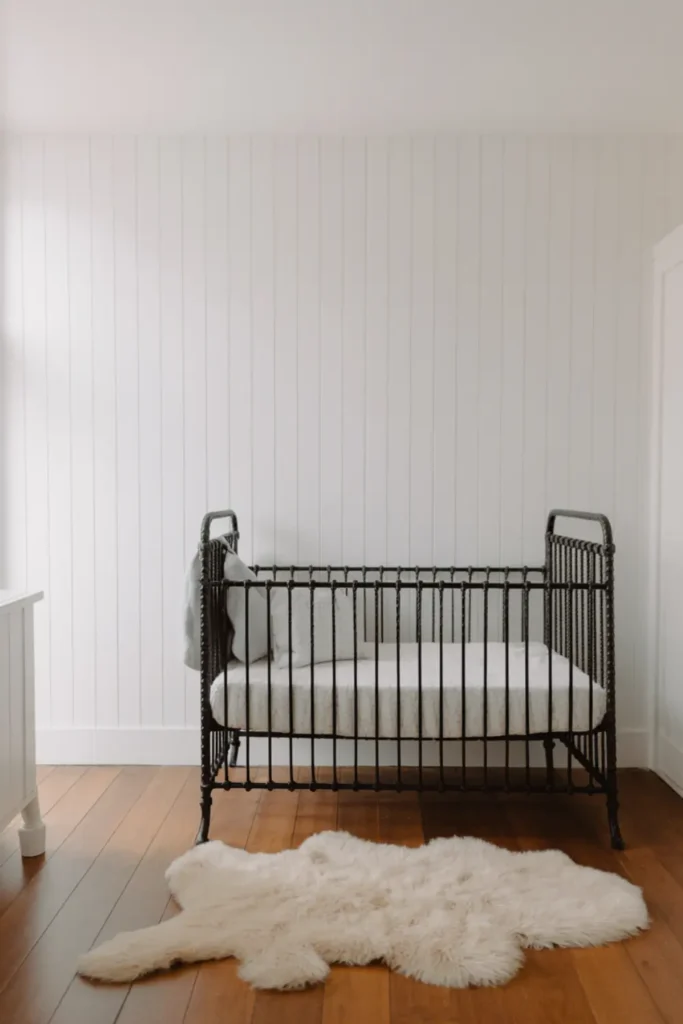 Farmhouse nursery with white shiplap walls.