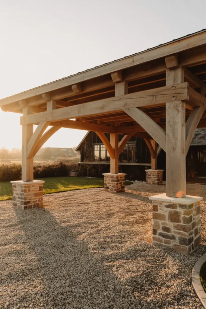 Rustic timber frame carport with stone bases on a gravel driveway