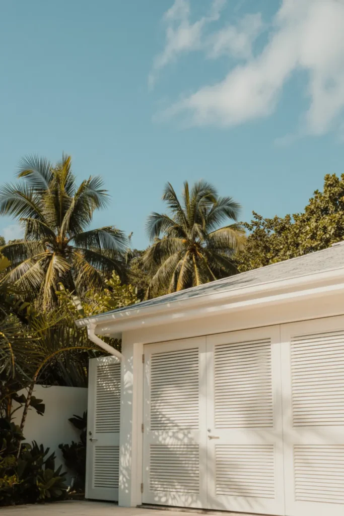 White louvered shutter-style garage doors on a coastal home.
