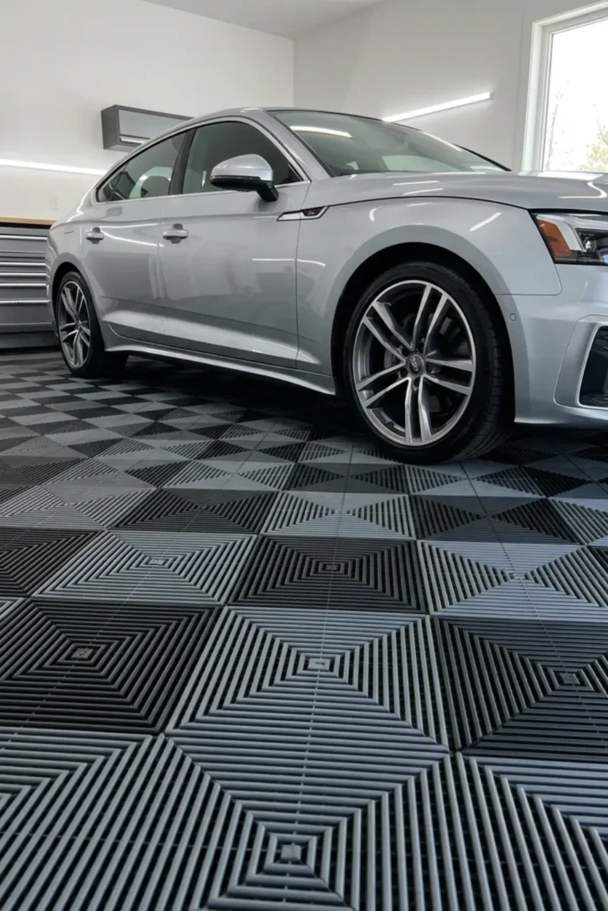 Interlocking black and gray modular garage floor tiles installed in a geometric pattern.