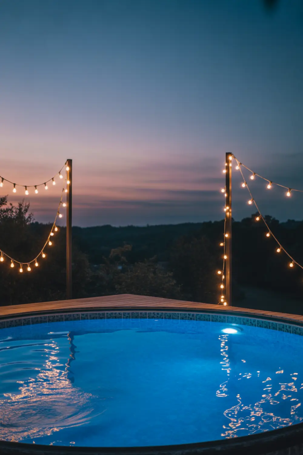 Above ground pool glowing at night with string lights.